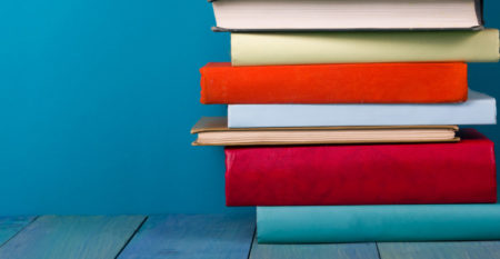 Stack of colorful books, grungy blue background, free copy space
